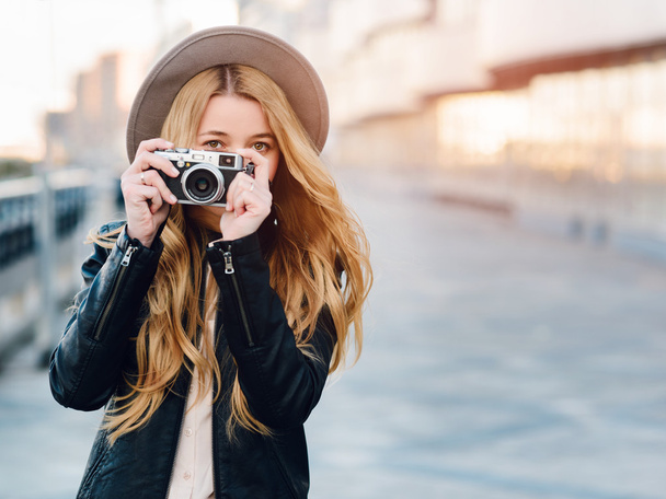 Menina bonita e jovem em um chapéu e uma câmera caminha e tira fotos
 - Foto, Imagem