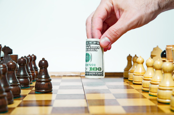 Man plays chess with hundred dollars bill and makes move - 写真・画像