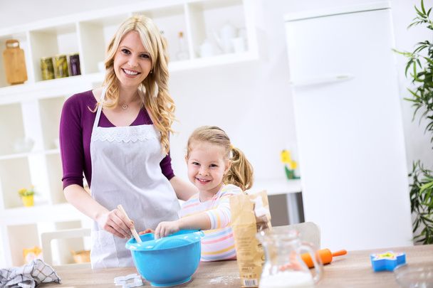 Smiling child and mother cooking together - Foto, imagen