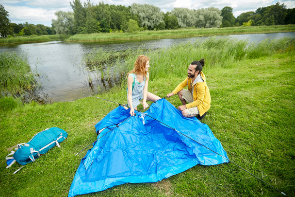 happy couple setting up tent outdoors - Fotoğraf, Görsel