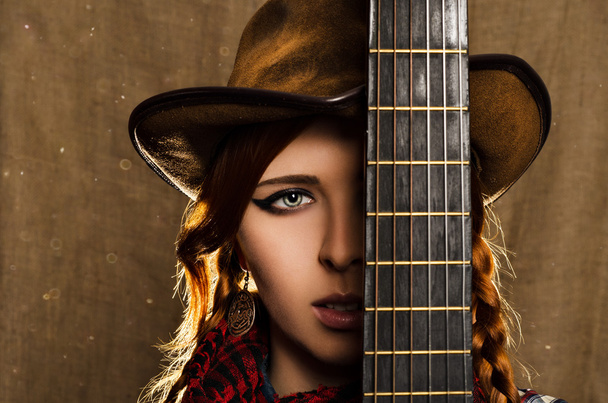 Portret van een mooi meisje met een gitaar in landelijke stijl - Foto, afbeelding