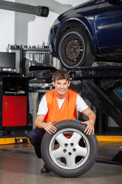 Happy Mechanic Holding Tire At Repair Shop - Zdjęcie, obraz