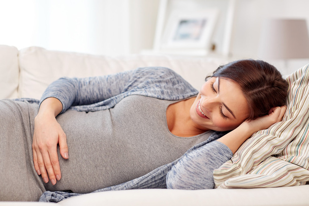 happy pregnant woman lying on sofa at home - Фото, изображение