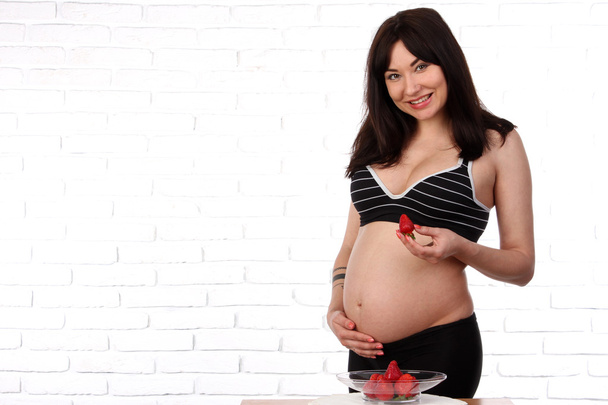 Mulher grávida comendo morango
 - Foto, Imagem