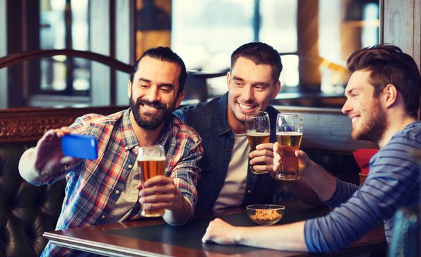 friends taking selfie and drinking beer at bar - Photo, image