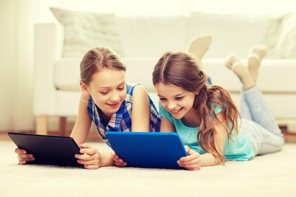 happy girls with tablet pc lying on floor at home - Foto, Imagen