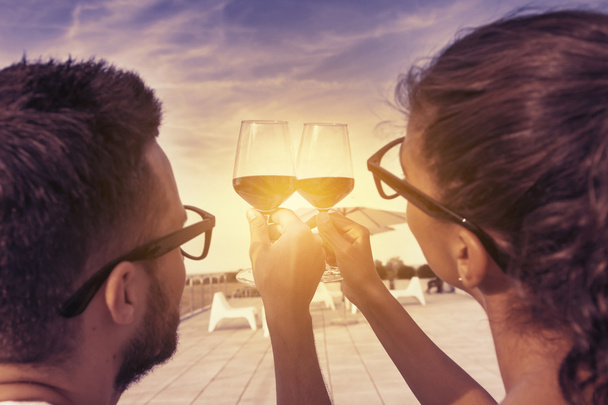 young couple toast on a terrace at sunset - Photo, image
