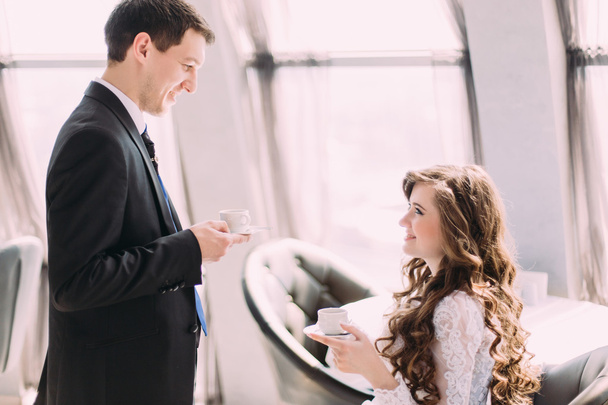 Handsome young groom in black suit brings his bride coffee - Foto, immagini