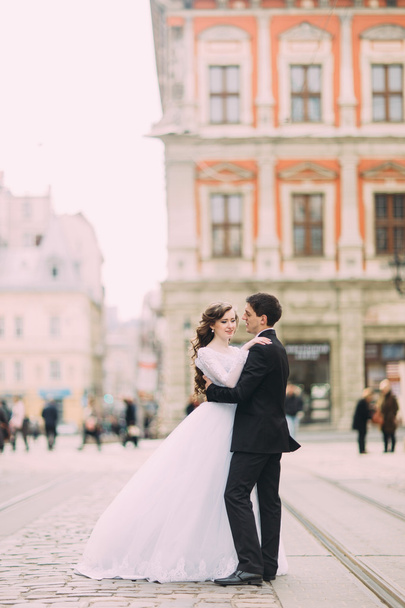 Happy bride and stylish groom running hugging on the background old sunny city - Foto, Imagem