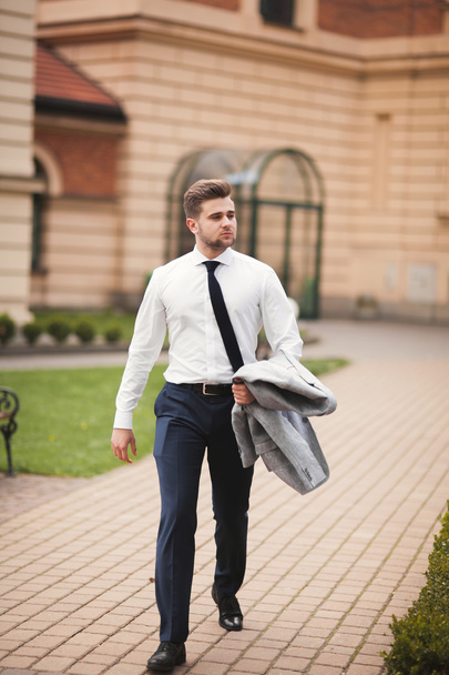 Stylish businessman walking outdoors and looking away - Fotó, kép