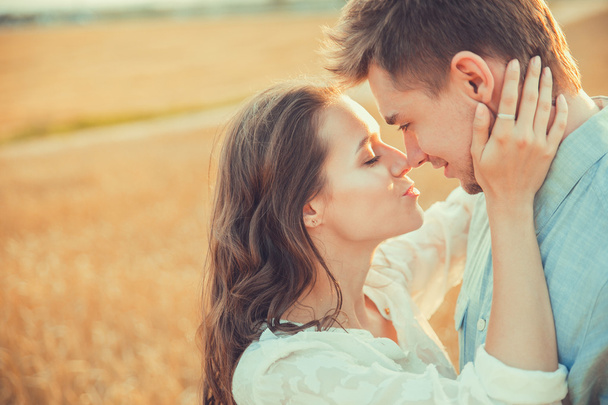 Young couple in love outdoor. Stunning sensual outdoor portrait of young stylish fashion couple posing in summer in field. Happy Smiling Couple in love. They are smiling and looking at each other - Fotografie, Obrázek