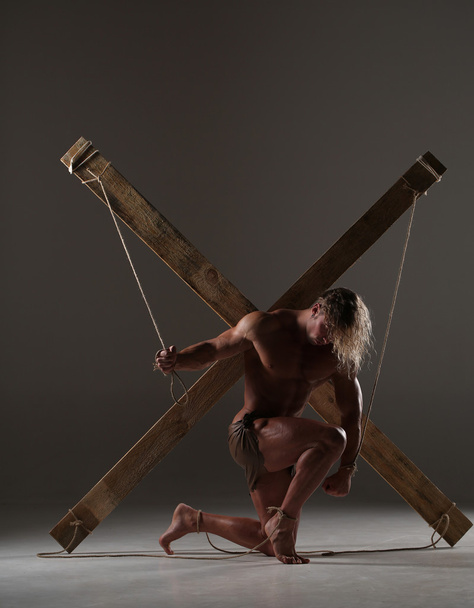 Sexual naked man, muscular, hands tied rope to wooden beams - Fotografie, Obrázek