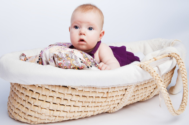 Little sweet girl a baby lying on a beautiful cushion in a wicke - Фото, изображение
