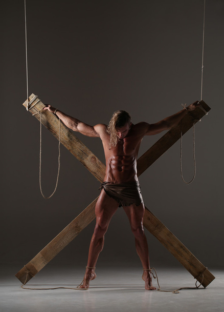 Sexual naked man, muscular, hands tied rope to wooden beams - Fotografie, Obrázek