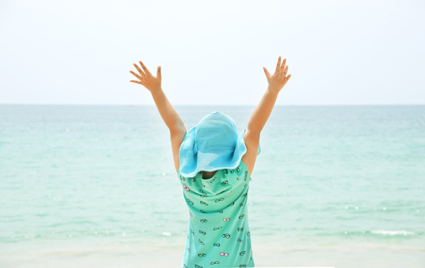 Menina com braços levantados perto do mar
 - Foto, Imagem