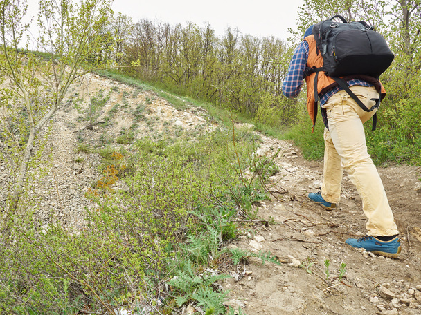 bir sırt çantası ile adam orman izi yokuş yukarı yürümek . - Fotoğraf, Görsel
