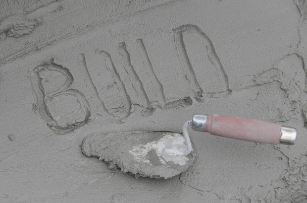 Inscripción de la palabra construir sobre cemento con paleta
 - Foto, Imagen