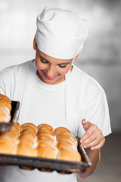 Female Baker Looking At Freshly Baked Breads - Foto, afbeelding