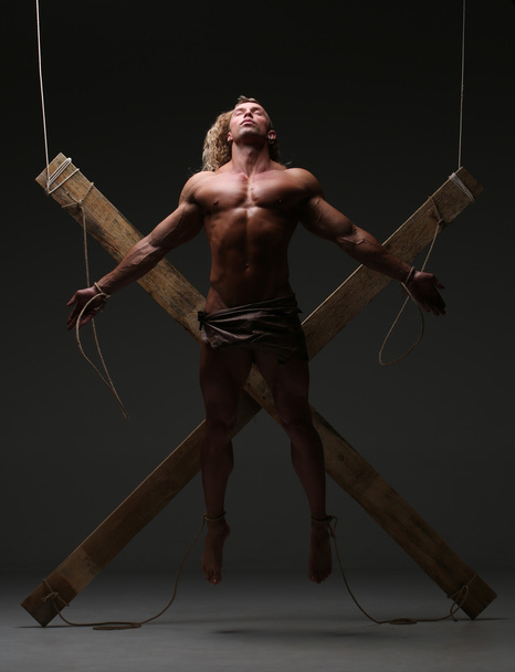 Sexual naked man, muscular, hands tied rope to wooden beams - Foto, Imagen