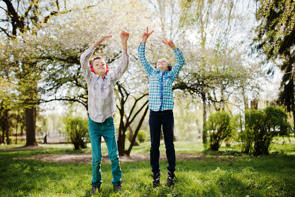 Two brother boy with headphones having fun and jump in air on pa - Foto, Imagen