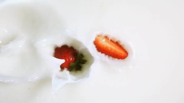 Pieces of strawberry drop into the milk - Footage, Video