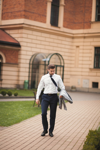 Stylish businessman walking outdoors and looking away - Zdjęcie, obraz