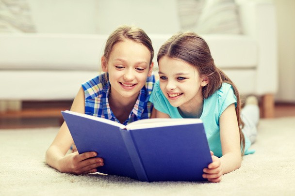 two happy girls reading book at home - Foto, imagen