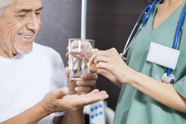 Buik van verpleegkundige geneeskunde en Water geven aan patiënt - Foto, afbeelding