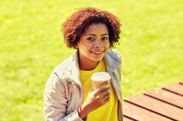 smiling african woman drinking coffee outdoors - Fotó, kép