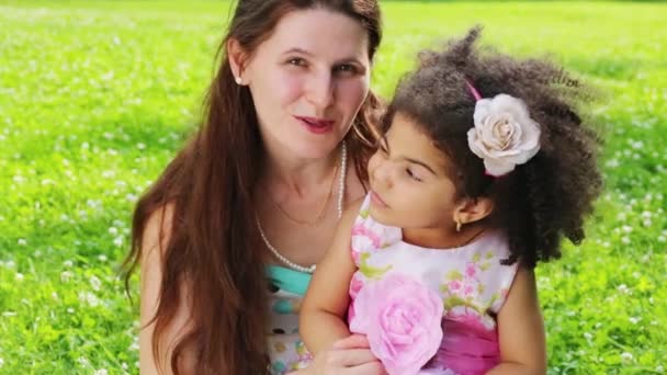 Mujer joven descansando en el parque con su hija en un día de verano
 - Metraje, vídeo