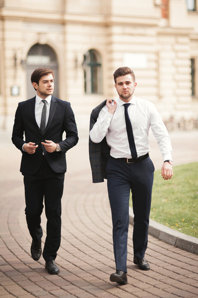 Two stylish businessmen speaking and smiling outdoors - 写真・画像