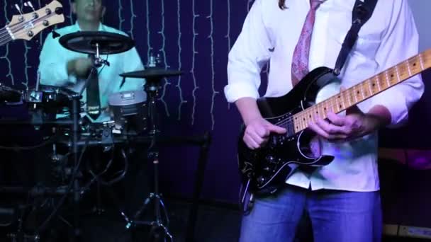 Hands of man playing guitar and drummer out of focus on show - Materiaali, video