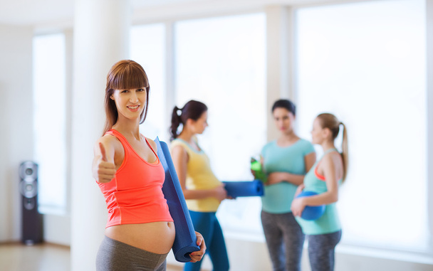 pregnant woman with mat showing thumbs up in gym - Φωτογραφία, εικόνα