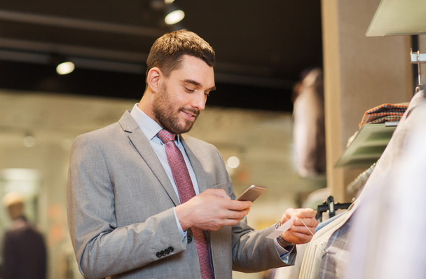 man in suit with smartphone at clothing store - Photo, image