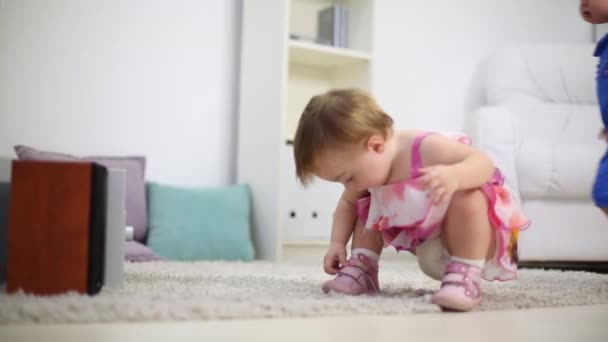 Two cute babies sit near stereo system on carpet in room at home - Materiał filmowy, wideo
