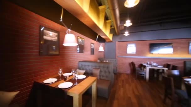 Sala spaziosa con tavoli serviti in legno e pareti di mattoni rossi
. - Filmati, video