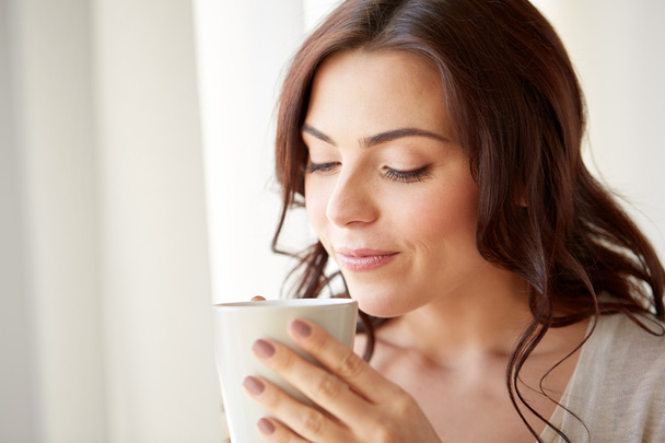 happy woman with cup of tea or coffee at home - Foto, Imagem
