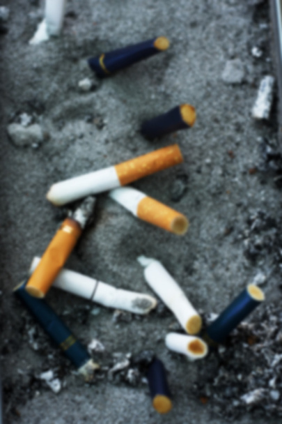 Blurred background of cigarette butts discarded in ashtray. - Photo, Image