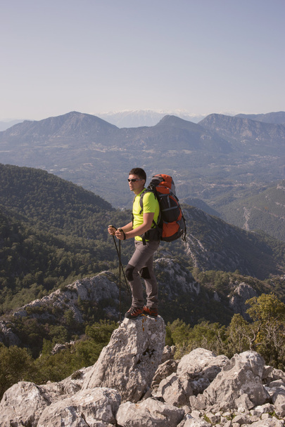 Young man with backpack on a mountain top on a sunny day.  - Foto, imagen