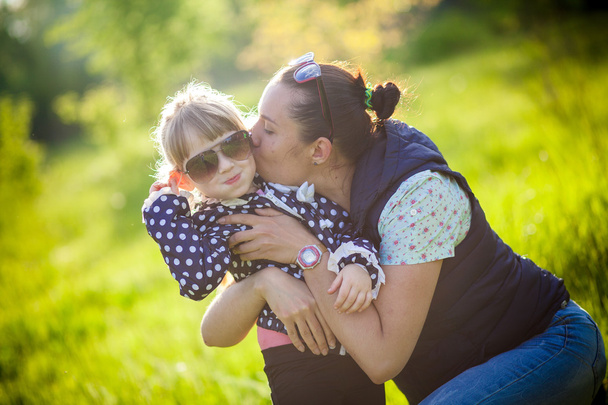 Little girl kissing her mother in park - Foto, afbeelding