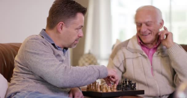 Senior man playing chess with his son - Záběry, video