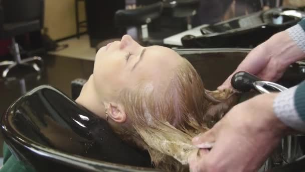professionelle Friseur reiben Shampoo in die Haare der blonden jungen Mädchen in Schönheitssalon. Massage des Kopfes - Filmmaterial, Video