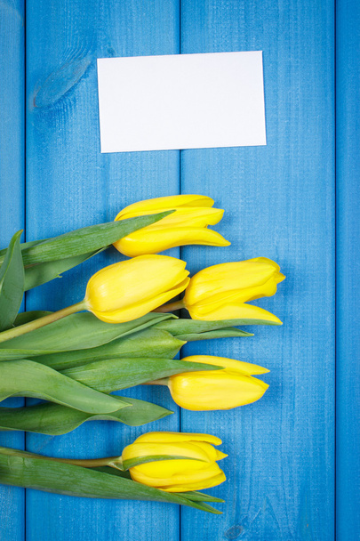 Bouquet of fresh tulips on blue wooden background, copy space for text on sheet of paper - Fotoğraf, Görsel