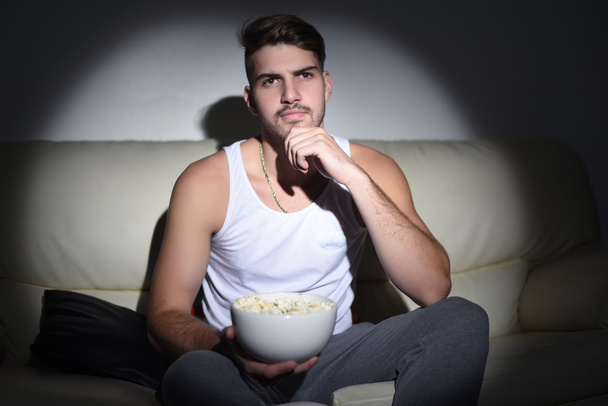 Young man eating popcorn and watching movies - Valokuva, kuva