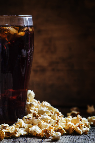 Large glass of cola, salty popcorn spilled on the table - Fotó, kép