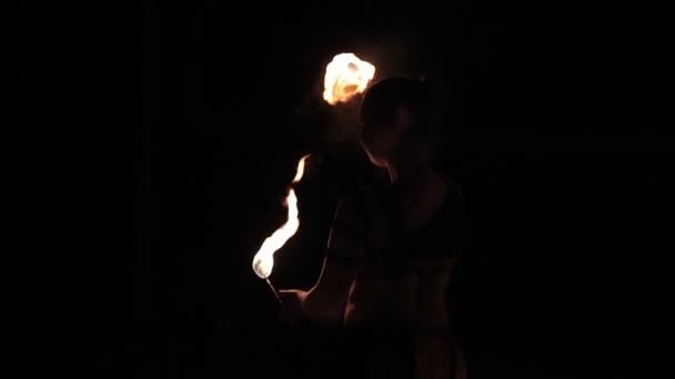 Desempenho de fogo. Mulher artista de fogo feminino dançando com tochas de fogo em chamas em um fundo preto. Close-up. Movimento lento
 - Filmagem, Vídeo