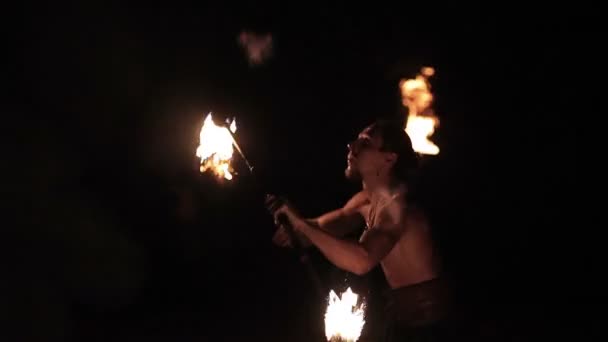 Fire show performance. Handsome male fire performer twirling fire baton ignited from both sides. Slow motion - Filmati, video