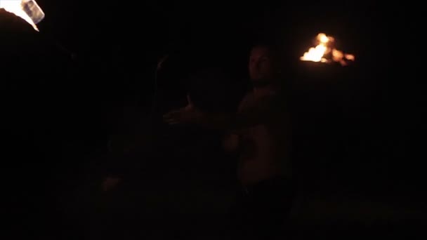 Fire show performance. Male fire performer spinning burning fire rope dart poi on long rope around himself. Slow motion - Filmagem, Vídeo