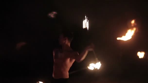 Fire show performance. Handsome male fire performer twirling and tossing up fire baton staff ignited from both sides. Slow motion - Footage, Video