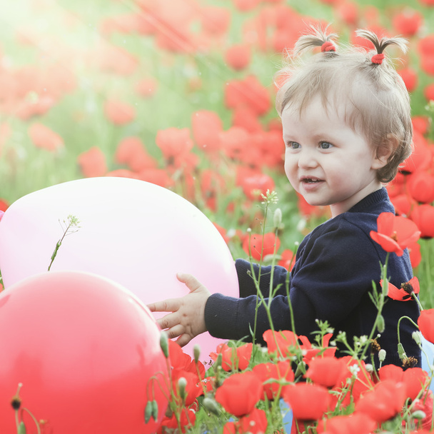 Funny child holding a balloon outdoor at poppy field - Foto, immagini